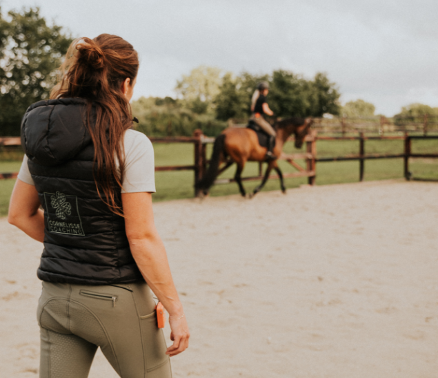 Mental Coach Kim Cornelisse werkt samen met een cliënt in de paardrijbak.