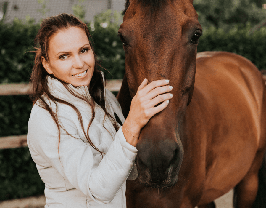 Kim Cornelisse lachend en aait een paard.